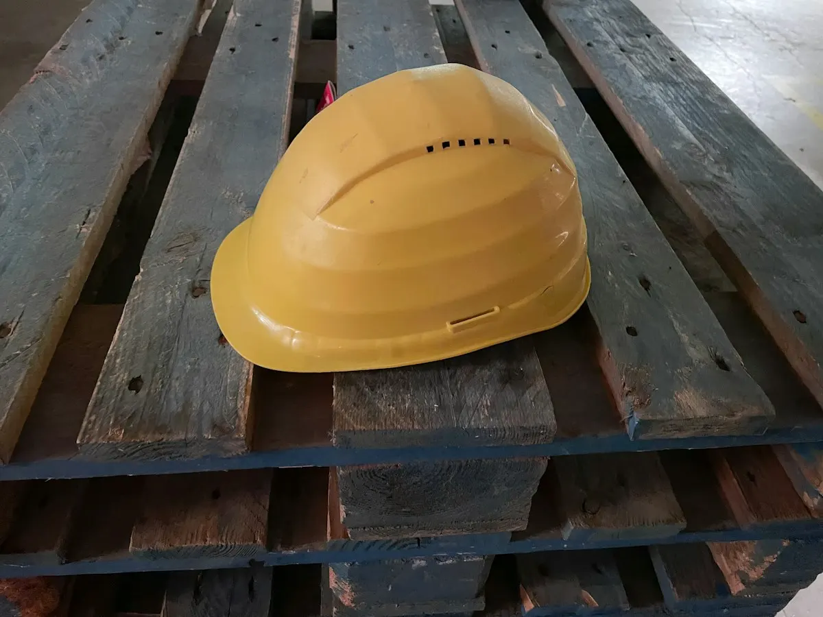 Casco de obra amarillo sobre un palé de madera